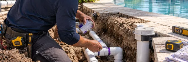 Exposed pool return and suction plumbing lines repaired in a backyard trench
