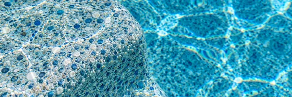 Close-up of pebble interior pool finish showing blue water color tone