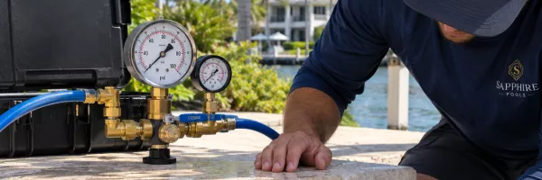 Technician pressure testing pool plumbing to locate a hidden water leak