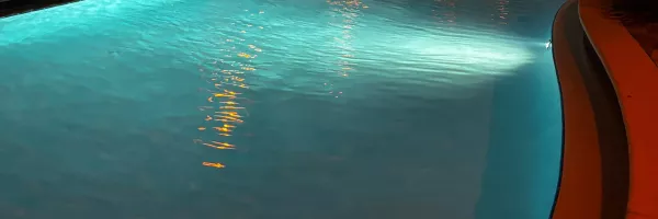 Backyard pool glowing with colored LED lighting at dusk in Florida