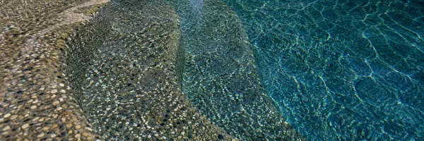 Pebble aggregate pool surface with textured stones and deep blue water