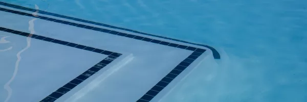 Smooth white plaster pool surface with clear blue water in sunlight