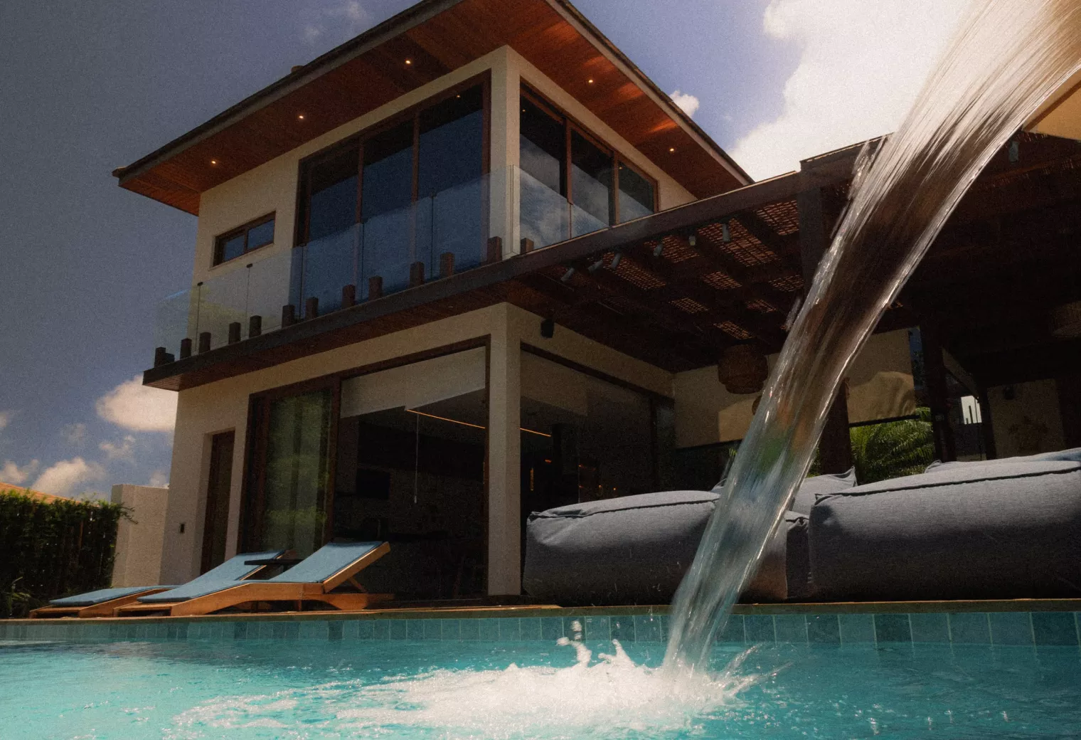 South Florida backyard pool with glowing sheer descent waterfall at dusk