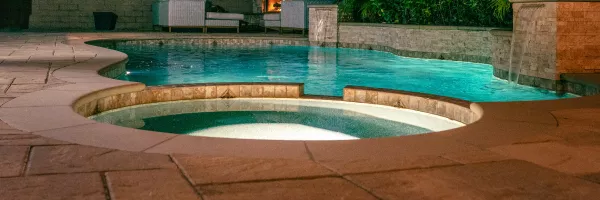 Raised spa attached to a concrete pool with spillover into main water