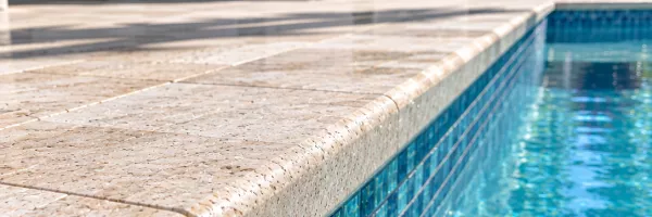 New glass waterline tile and stone coping along a remodeled pool edge