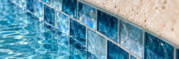 Glass waterline tile meeting stone coping at the edge of pool