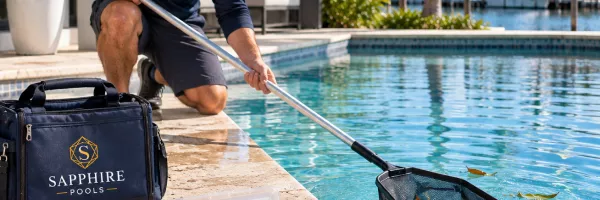 Weekly pool cleaning with net and test kit on Florida pool deck