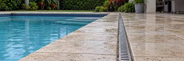 Pool deck drain channel carrying rainwater away from leveled pavers