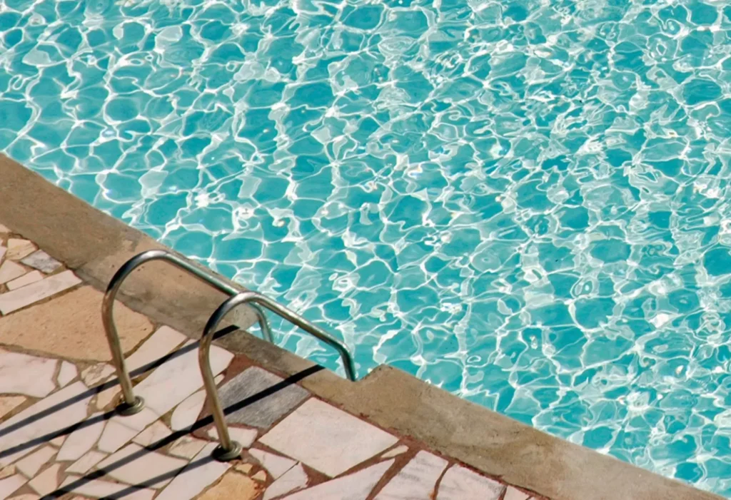 Light textured coated pool deck beside a sunny pool