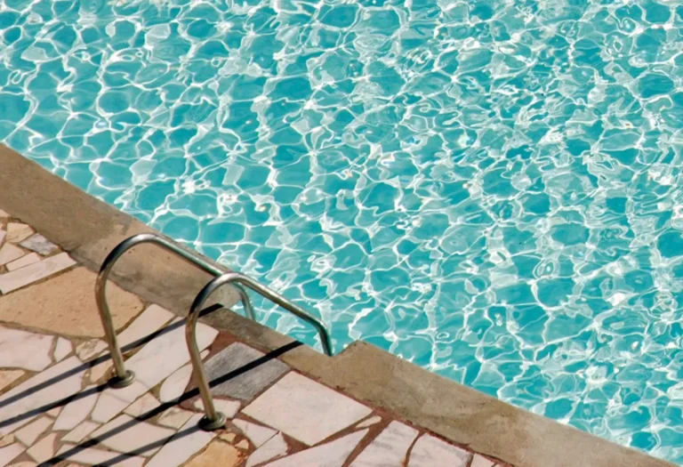 Light textured coated pool deck beside a sunny pool