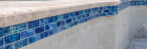 Fresh blue waterline tile installed just beneath new pool coping